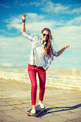 Image showing smiling teenage girl riding skate outside