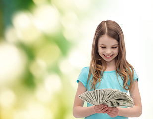 Image showing smiling little girl looking at dollar cash money