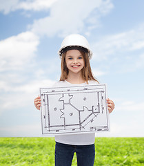 Image showing smiling little girl in helmet showing blueprint