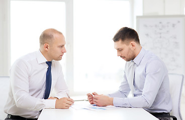 Image showing two serious businessman with papers in office