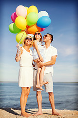 Image showing happy family with colorful balloons at seaside