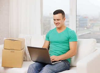 Image showing man with laptop and cardboard boxes at home