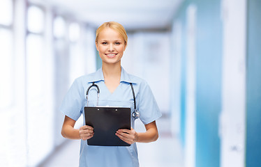 Image showing smiling female doctor or nurse with clipboard