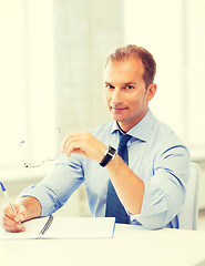 Image showing businessman with spectacles writing in notebook