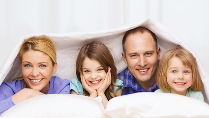 Image showing happy family with two kids under blanket at home