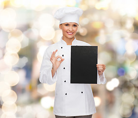 Image showing smiling female chef with black blank paper