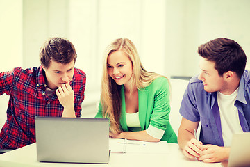 Image showing smiling students looking at laptop at school