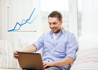 Image showing smiling man working with laptop at home