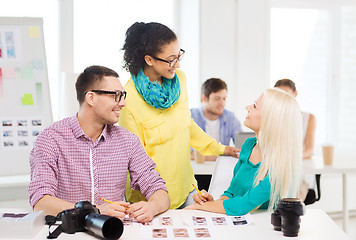 Image showing smiling team with printed photos working in office