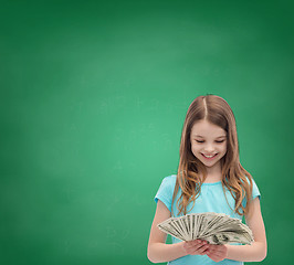 Image showing smiling little girl looking at dollar cash money