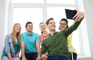 Image showing smiling students making picture with tablet pc