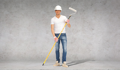 Image showing handsome painter in helmet with paint roller