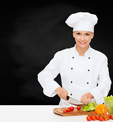 Image showing smiling female chef chopping vegetables