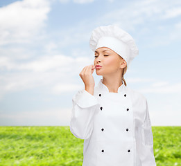 Image showing smiling female chef showing delicious sign