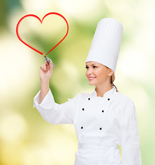 Image showing smiling female chef writing something on air