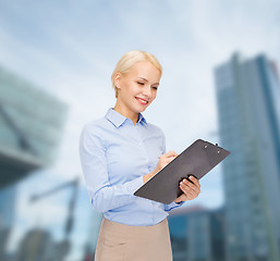 Image showing smiling businesswoman with clipboard and pen