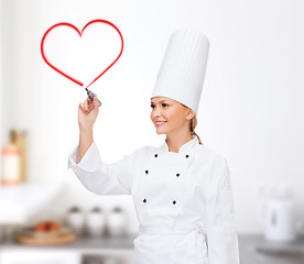 Image showing smiling female chef writing something on air