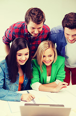 Image showing smiling students looking at laptop at school