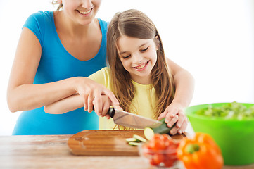 Image showing smiling little girl with mother chopping cucumber