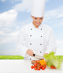 Image showing smiling female chef chopping vegetables