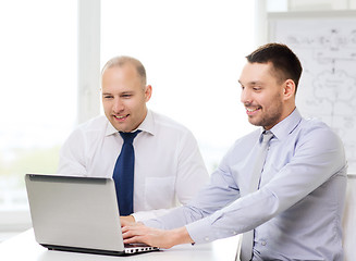 Image showing two smiling businessmen with laptop in office