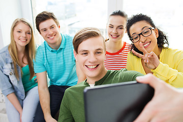 Image showing smiling students making picture with tablet pc