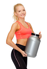 Image showing smiling sporty woman with jar of protein