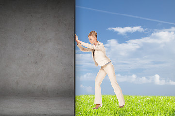 Image showing businesswoman pushing away concrete wall