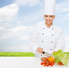 Image showing smiling female chef chopping vegetables