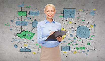 Image showing smiling businesswoman with clipboard and pen