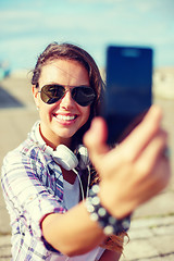 Image showing smiling teenager taking picture with smartphone