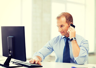 Image showing smiling businessman with smartphone in office