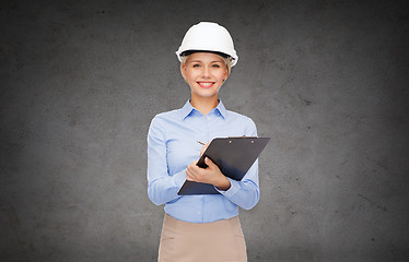 Image showing smiling businesswoman in helmet with clipboard