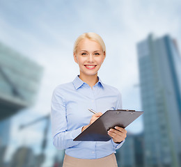 Image showing smiling businesswoman with clipboard and pen