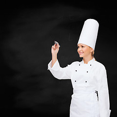 Image showing smiling female chef writing something on air