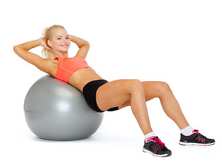 Image showing smiling sporty woman exercising on fitness ball