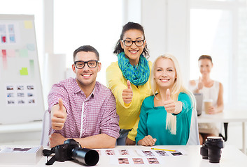 Image showing smiling team with printed photos working in office