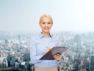 Image showing smiling businesswoman with clipboard and pen