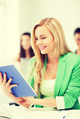 Image showing smiling young girl reading book at school