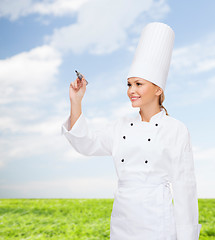 Image showing smiling female chef writing something on air