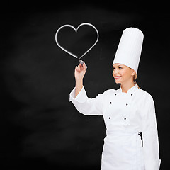 Image showing smiling female chef writing something on air