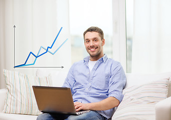 Image showing smiling man working with laptop at home