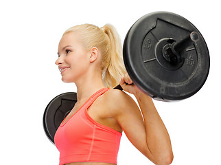 Image showing smiling sporty woman exercising with barbell