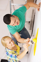 Image showing smiling couple painting wall at home