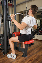 Image showing Young man doing lats pull-down workout in gym