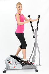 Image showing young woman doing exercises on elliptical trainer