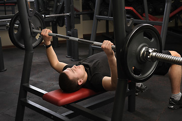 Image showing young man doing bench press workout in gym