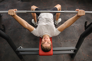 Image showing young man doing bench press workout in gym