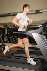 Image showing young man running at treadmill in gym