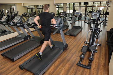 Image showing young man running at treadmill in gym